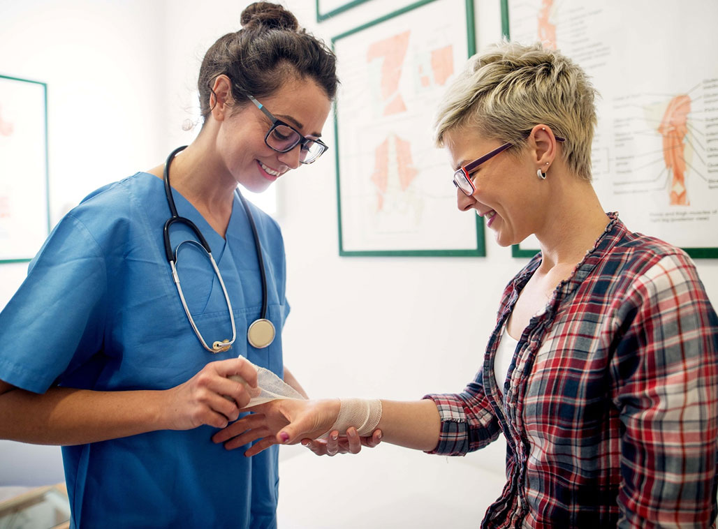 medical nurse putting a bandage on a young girl's injured hand